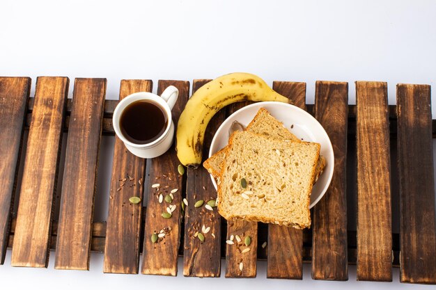 Healthy tasty morning breakfast with multigrain bread black coffee and banana on wooden