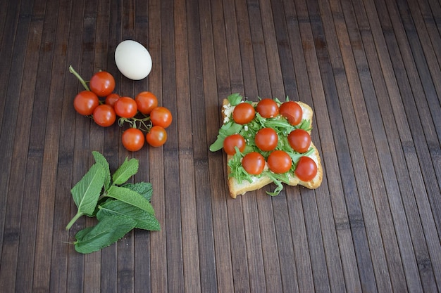 Foto toast salutare per colazione con pomodori, rucola ed erbe aromatiche