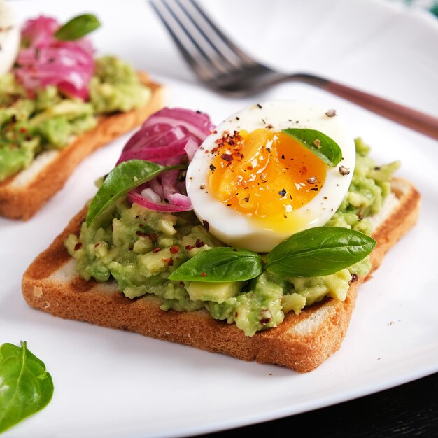 Healthy toast with mashed avocado boiled eggs spices and red onions Delicious breakfast or snack