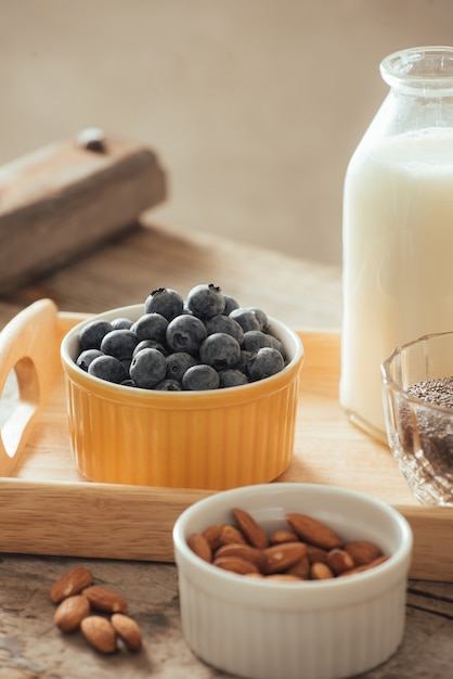 Colazione vegana sana. latte in bottiglia con chia, mandorle, frutta fresca e bacche su sfondo tavolo in legno, spazio copia. cibo pulito, perdita di peso, vegetariano, concetto di cibo crudo