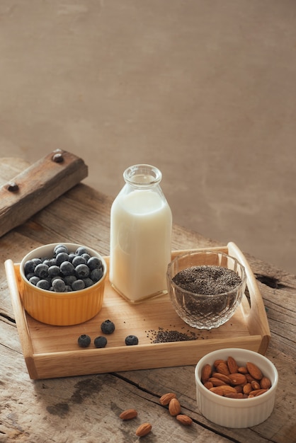 Healthy vegan breakfast. Bottled milk with chia, almond, fresh fruit and berries over wooden table background, copy space. Clean eating, weight loss, vegetarian, raw food concept