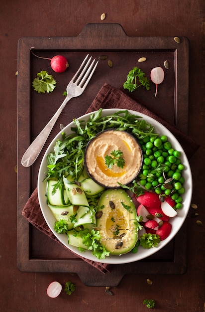 Healthy vegan lunch bowl with avocaco cucumber hummus peas radish