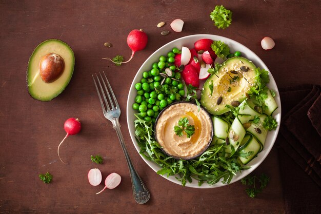 Healthy vegan lunch bowl with avocaco cucumber hummus peas radish