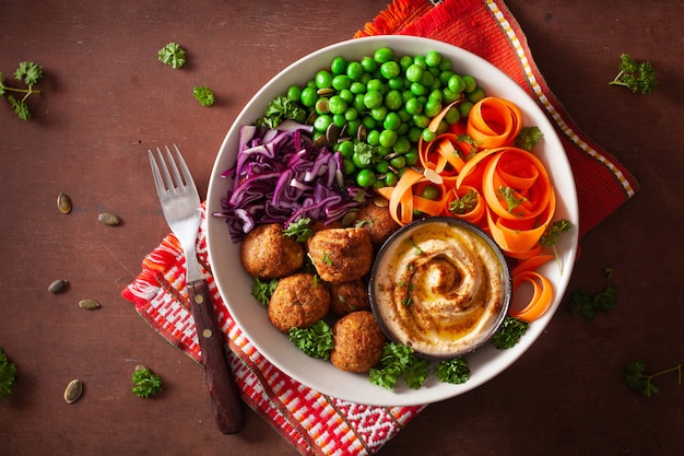 Healthy vegan lunch bowl with falafel hummus carrot ribbons cabbage and peas