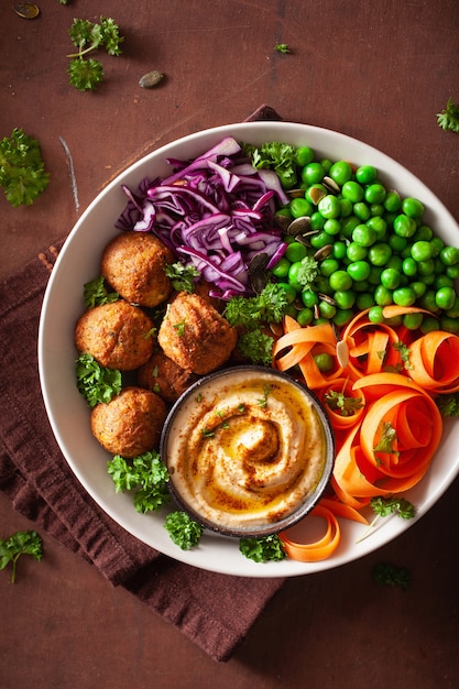 Ciotola di pranzo vegana sana con falafel hummus carota nastri cavolo e piselli