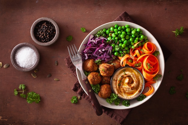 Healthy vegan lunch bowl with falafel hummus carrot ribbons cabbage and peas