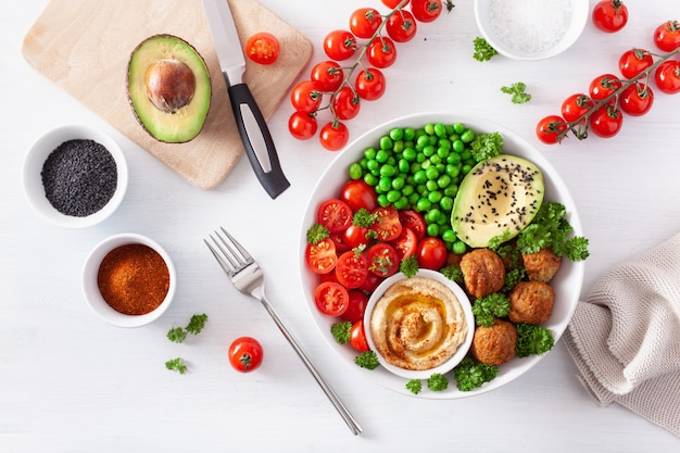 Healthy vegan lunch bowl with falafel hummus tomato avocado peas