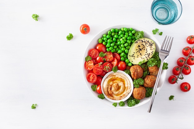 Healthy vegan lunch bowl with falafel hummus tomato avocado peas