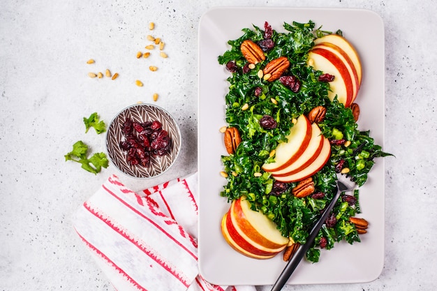 Healthy vegan salad with apple, cranberry, kale and pecan in a rectangular plate, top view.