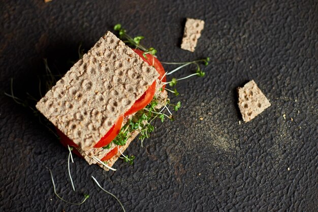 Healthy vegan sandwich with crisp rye bread tomatoe and microgreens