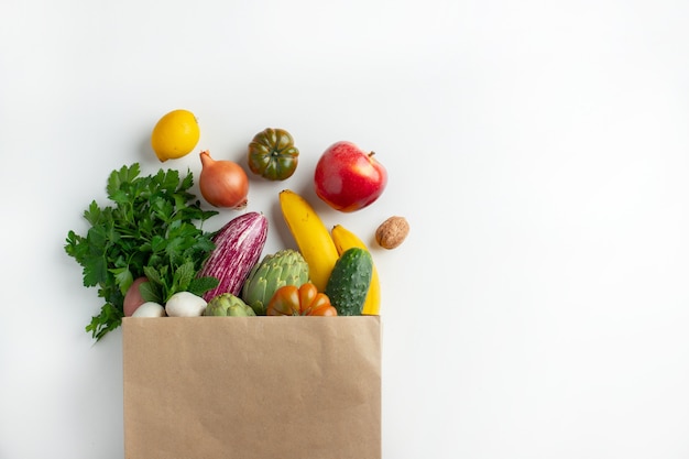 Здоровая веганская вегетарианская еда в бумажных пакетах овощей и фруктов на белом, копией пространства. Шоппинг продуктовый супермаркет и концепция чистой веганской еды.