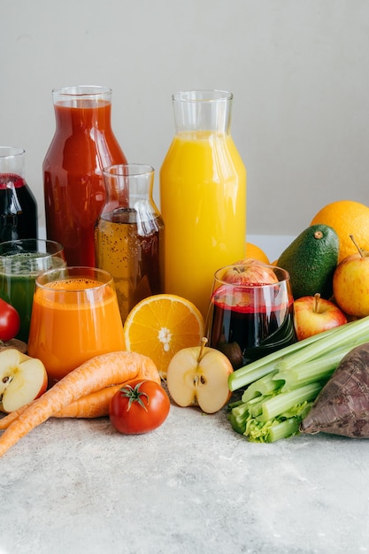 Healthy vegetable and fruit juices or smoothie in glass bottles ripe slices of orange apple red tomato carrot celery avocado isolated on white background