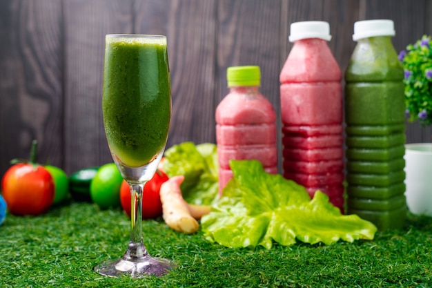 Healthy vegetable juices with fruit around on grass