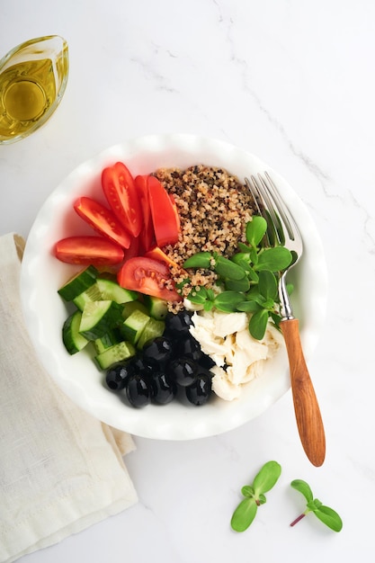 Healthy vegetable lunch from the Buddha bowl with with tomato cucumber mozzarella cheese quinoa olives and microgreens Vegan salad buddha bowl Healthy and balanced food concept