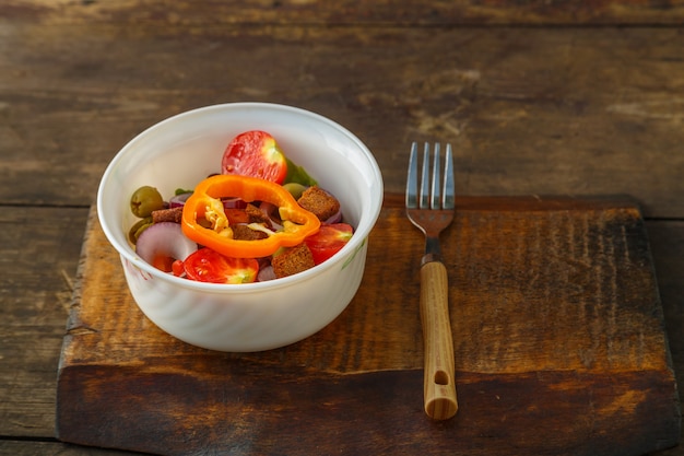 Healthy vegetable salad in a salad bowl on a wooden table next\
to a fork. horizontal photo