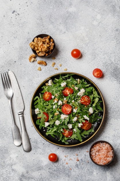 Healthy vegetable salad with fresh arugula, tomato, feta cheese and walnut