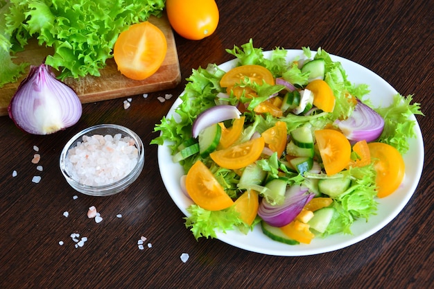 healthy vegetable salad with yellow tomato, spanish onion, green salad and cucumber, close-up