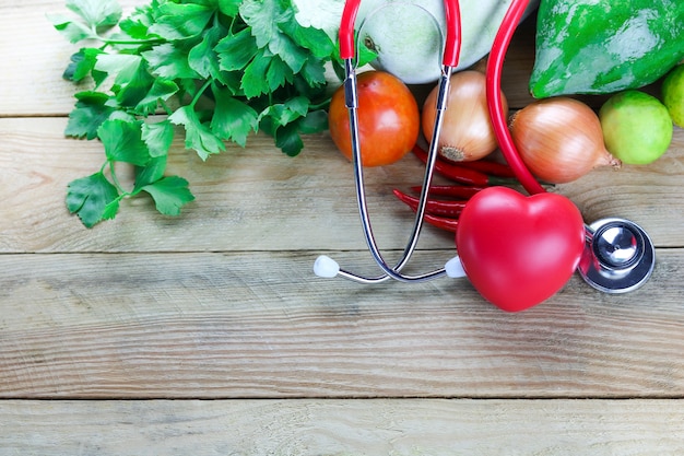 healthy vegetable with red heart and stethoscope on wood table