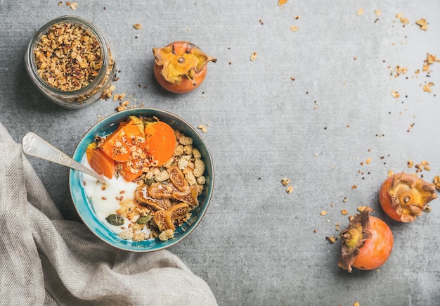 Healthy vegetarian breakfast in blue bowl and fresh persimmon