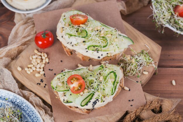 Healthy vegetarian bruschettas with bread, hummus, cherry tomatoes, cucumbers and pine nuts