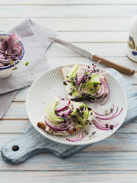 Healthy vegetarian bruschettas with bread, micro greens, cheese, cucumbers and red onion