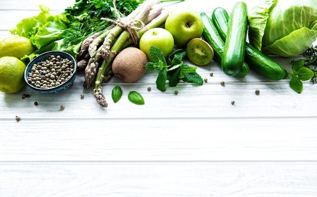 Healthy vegetarian food concept background, fresh green food selection for detox diet,  apple, cucumber, asparagus, avocado, lime,  salad  top view on a white wooden  background