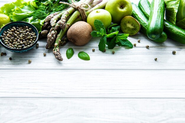 Healthy vegetarian food concept surface, fresh green food selection for detox diet,  apple, cucumber, asparagus, avocado, lime,  salad  top view on a white wooden  surface