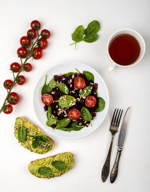 Здоровая вегетарианская еда. салат из свеклы, шпината, помидоров черри и семян.