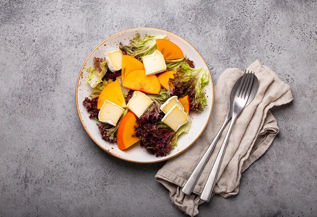 Healthy vegetarian persimmon salad with brie top view