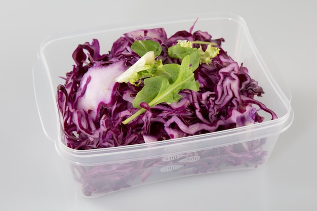 Фото Здоровый вегетарианский салат с красной капустой, нарезанный в пластиковой коробке на вынос
