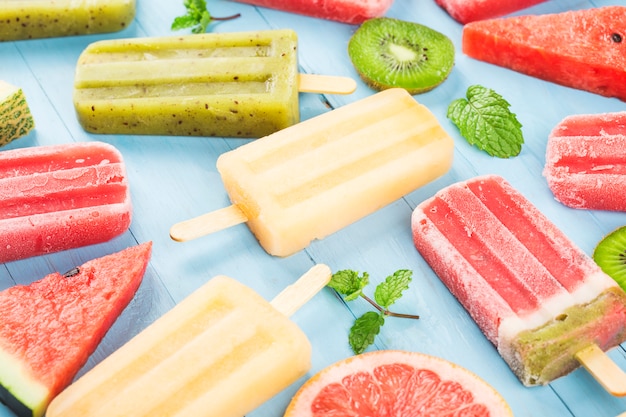 Healthy Whole Fruit Popsicles with Berries Kiwi watermelon cantaloupe on wooden vintage table