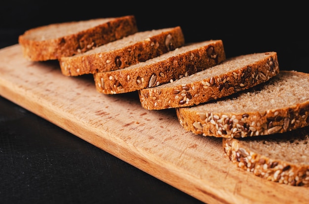 Healthy whole grain dark bread with seeds on black.