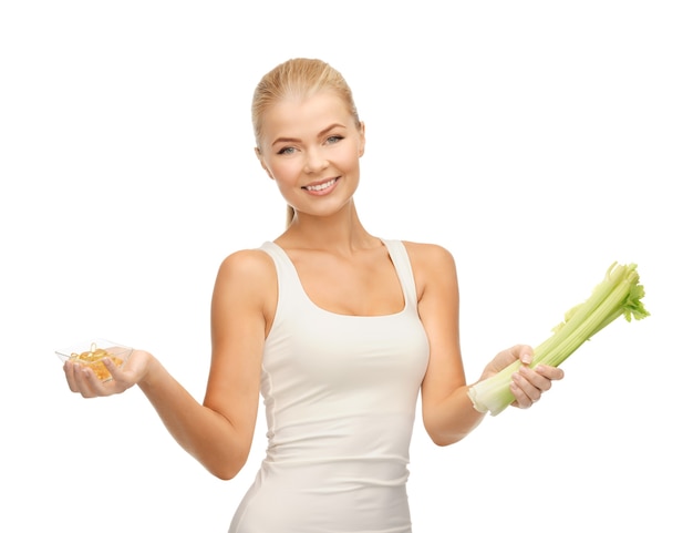 healthy woman holding bunch of celery and vitamins