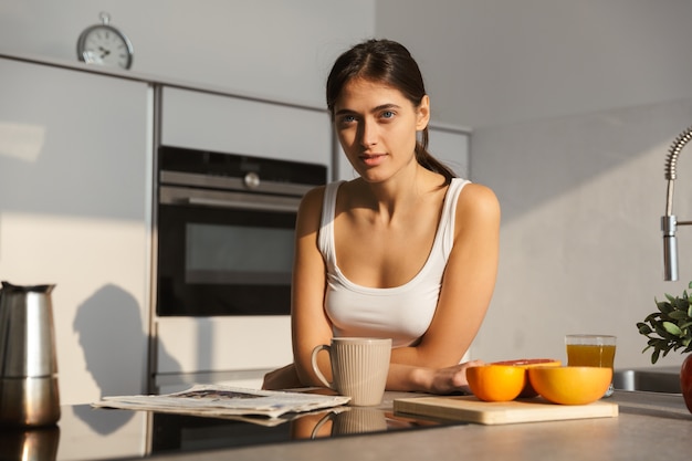 Фото Здоровая женщина на кухне, стоя повседневной утренней рутины.