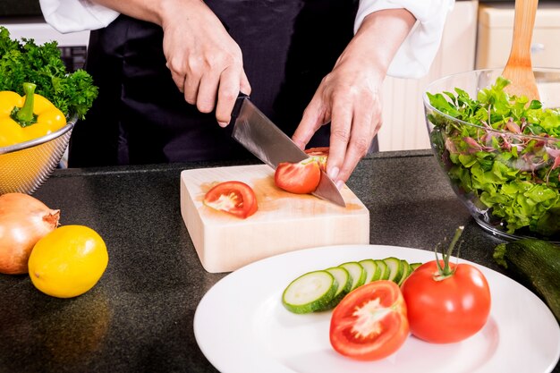 ヘルシーな女性は、オリーブオイル、トマト、サラダなどの野菜サラダを作ります。