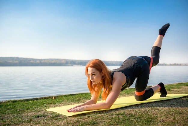 Donna in buona salute che riposa e che fa stretching esercizio all'aperto vicino al lago