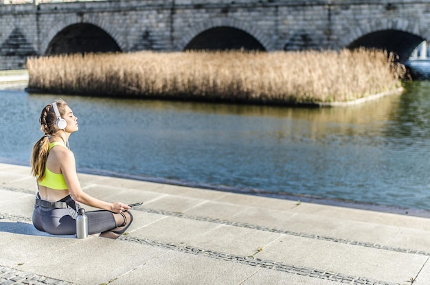 Foto donna sana che si riposa e ascolta musica con il cellulare mentre fa yoga e allenamento