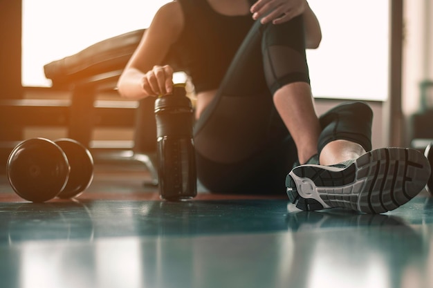 Le donne sane sono sedute e si rilassano dopo aver fatto esercizio con proteine del siero di latte dopo gli allenamenti in palestra al coperto.