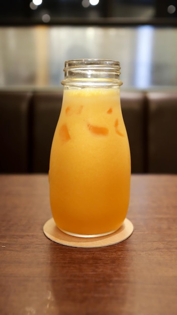 ガラスのボトルにめ込まれた健康的な黄色いオレンジジュース