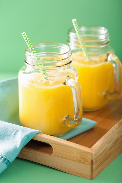 Healthy yellow smoothie with mango pineapple banana in mason jars