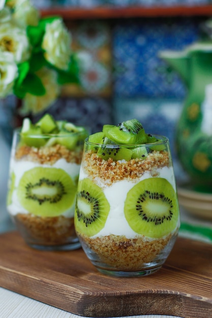 Healthy yogurt dessert with granola and fresh cut kiwi in tall glasses.