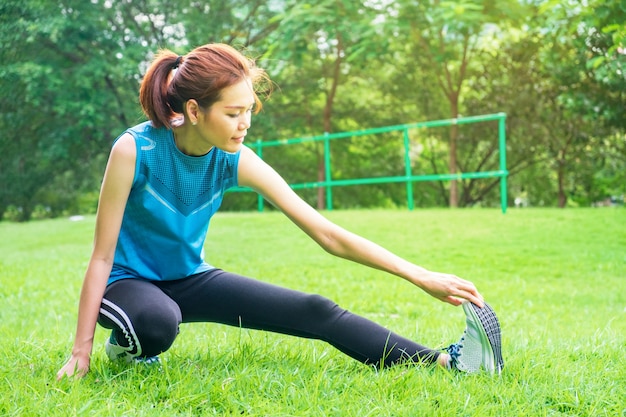 写真 屋外で公園で走る前にウォームアップしている健康的な若いアジアの女性ランナー
