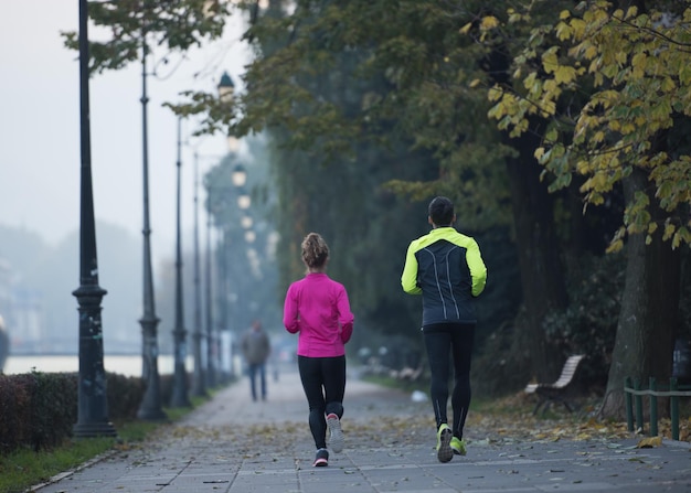 Giovane coppia in buona salute che fa jogging in città al mattino presto con l'alba sullo sfondo