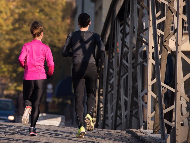 healthy young  couple jogging in the city  at early morning with sunrise in background
