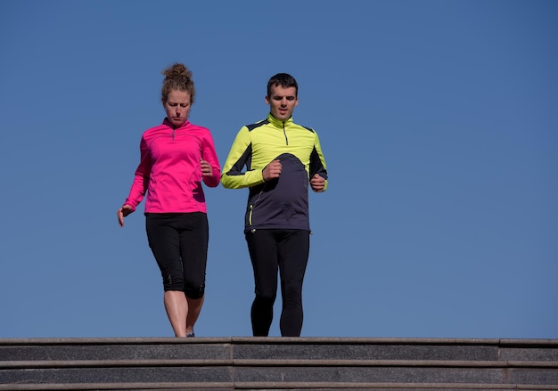 healthy young  couple jogging on steps  at early morning