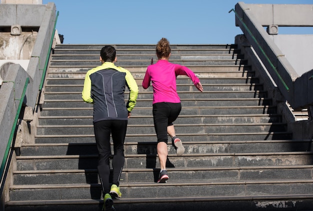 healthy young  couple jogging on steps  at early morning