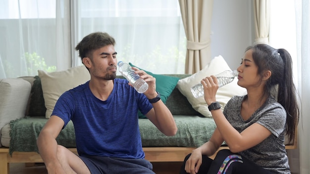 Healthy young couple in sportswear resting and drinking water after morning workout