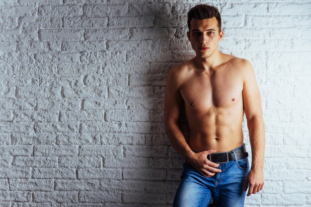 Healthy young guy posing near a white wall