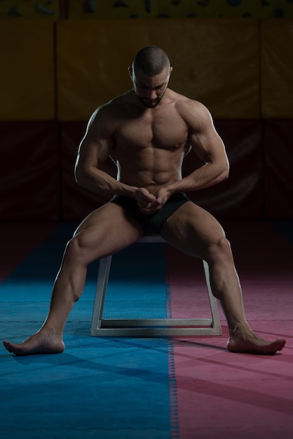 Healthy Young Man Standing Strong In The Gym And Flexing Muscles  Muscular Athletic Bodybuilder Fitness Model Posing After Exercises