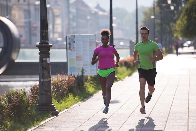 healthy young multiethnic couple jogging in the city on a sunny summer day